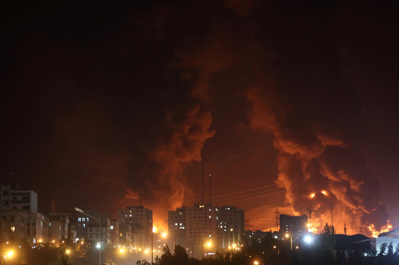 Orang-orang menyaksikan dari jembatan saat api dari serangan Israel membubung dari depot minyak Sharan, menyusul serangan Israel terhadap Iran, di Teheran, Iran, 15 Juni 2025. Orang-orang menyaksikan dari jembatan saat api dari serangan Israel membubung dari depot minyak Sharan, menyusul serangan Israel terhadap Iran, di Teheran, Iran, 15 Juni 2025. (Majid Asgaripour/WANA (West Asia News Agency) via REUTERS)