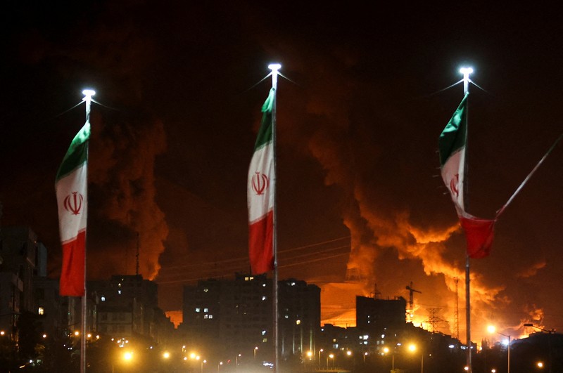 Orang-orang menyaksikan dari jembatan saat api dari serangan Israel membubung dari depot minyak Sharan, menyusul serangan Israel terhadap Iran, di Teheran, Iran, 15 Juni 2025. Orang-orang menyaksikan dari jembatan saat api dari serangan Israel membubung dari depot minyak Sharan, menyusul serangan Israel terhadap Iran, di Teheran, Iran, 15 Juni 2025. (Majid Asgaripour/WANA (West Asia News Agency) via REUTERS)