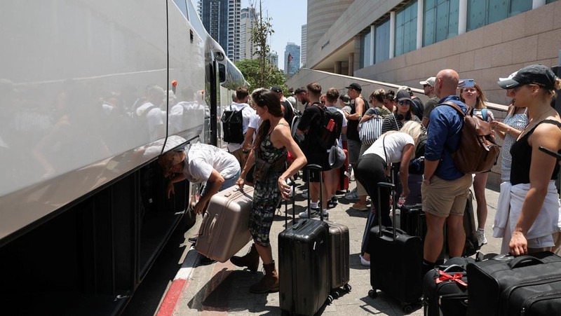ang-orang dengan kewarganegaraan asing berkumpul untuk meninggalkan Israel dengan bus melalui Mesir, setelah serangan rudal dari Iran, di Tel Aviv, Israel, Selasa (17/6/2925). (REUTERS/Ronen Zvulun)