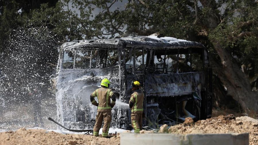 Petugas pemadam kebakaran berupaya memadamkan api di sebuah bus setelah serangan rudal dari Iran, di Herzliya, Israel, Selasa (17/6/2025). (REUTERS/Ronen Zvulun)