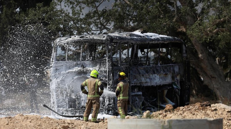 Petugas pemadam kebakaran berupaya memadamkan api di sebuah bus setelah serangan rudal dari Iran, di Herzliya, Israel, Selasa (17/6/2025). (REUTERS/Ronen Zvulun)