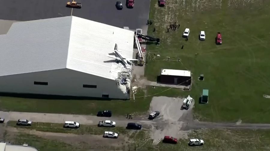 Sebuah pesawat jatuh dan tersangkut di atas atap sebuah hanggar dalam sebuah insiden mengejutkan yang terjadi di Bandara New Century, AS Senin (16/6/2025). (Tangkapan Layar Video Reuters/ABC AFFILIATE KMBC)