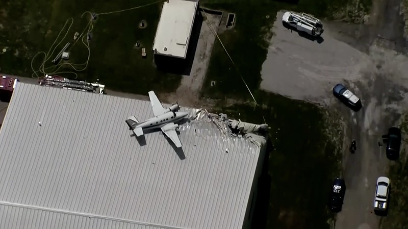 Sebuah pesawat jatuh dan tersangkut di atas atap sebuah hanggar dalam sebuah insiden mengejutkan yang terjadi di Bandara New Century, AS Senin (16/6/2025). (Tangkapan Layar Video Reuters/ABC AFFILIATE KMBC)