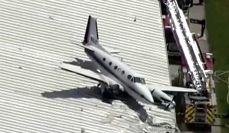 Sebuah pesawat jatuh dan tersangkut di atas atap sebuah hanggar dalam sebuah insiden mengejutkan yang terjadi di Bandara New Century, AS Senin (16/6/2025). (Tangkapan Layar Video Reuters/ABC AFFILIATE KMBC)