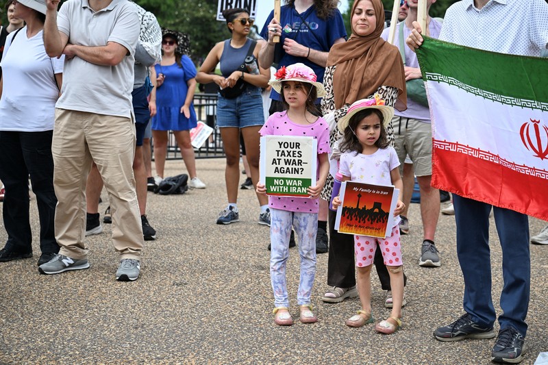 Marinir AS berjaga saat seorang demonstran memegang plakat selama protes terhadap Amerika Serikat yang bergabung dengan Israel dalam serangan terhadap fasilitas nuklir Iran, di gedung federal di Los Angeles, California, AS, 22 Juni 2025. (REUTERS/David Swanson)
