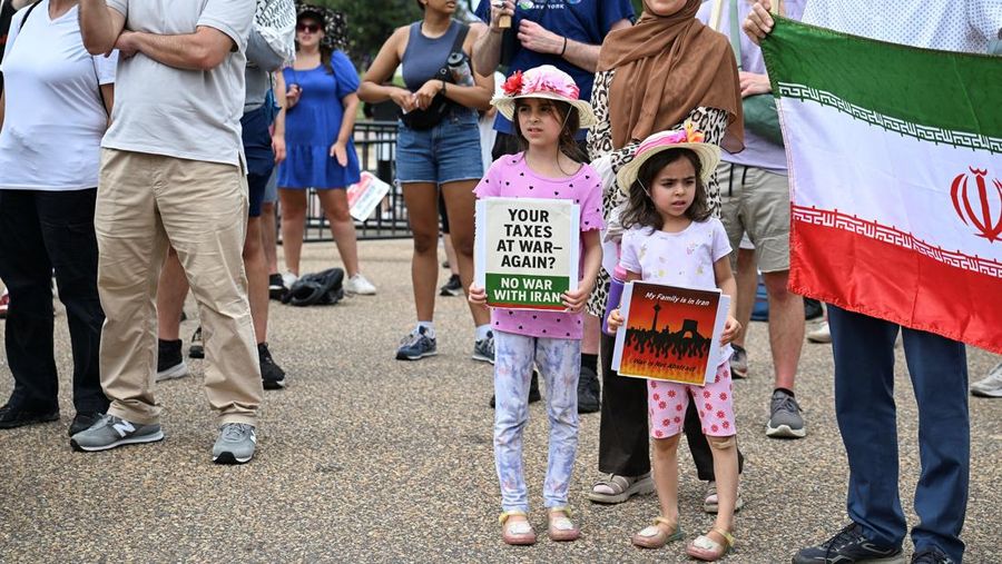 Marinir AS berjaga saat seorang demonstran memegang plakat selama protes terhadap Amerika Serikat yang bergabung dengan Israel dalam serangan terhadap fasilitas nuklir Iran, di gedung federal di Los Angeles, California, AS, 22 Juni 2025. (REUTERS/David Swanson)