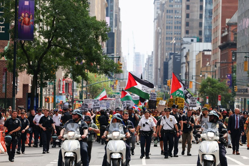 Marinir AS berjaga saat seorang demonstran memegang plakat selama protes terhadap Amerika Serikat yang bergabung dengan Israel dalam serangan terhadap fasilitas nuklir Iran, di gedung federal di Los Angeles, California, AS, 22 Juni 2025. (REUTERS/David Swanson)