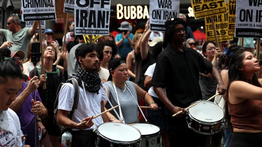 Marinir AS berjaga saat seorang demonstran memegang plakat selama protes terhadap Amerika Serikat yang bergabung dengan Israel dalam serangan terhadap fasilitas nuklir Iran, di gedung federal di Los Angeles, California, AS, 22 Juni 2025. (REUTERS/David Swanson)