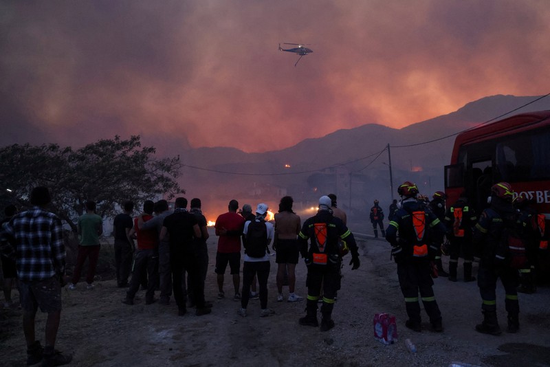 Petugas pemadam kebakaran bekerja untuk memadamkan kebakaran hutan, yang dipicu oleh angin kencang, yang menyebabkan munculnya pesan evakuasi di dekat desa Karyes di pulau Chios, Yunani, 22 Juni 2025. Petugas pemadam kebakaran bekerja untuk memadamkan kebakaran hutan, yang dipicu oleh angin kencang, yang menyebabkan munculnya pesan evakuasi di dekat desa Karyes di pulau Chios, Yunani, 22 Juni 2025. (REUTERS/Kostas Anagnostou)