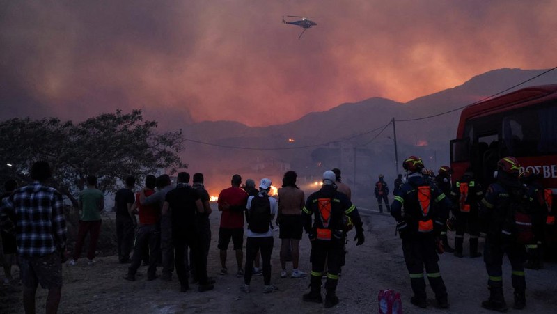 Petugas pemadam kebakaran bekerja untuk memadamkan kebakaran hutan, yang dipicu oleh angin kencang, yang menyebabkan munculnya pesan evakuasi di dekat desa Karyes di pulau Chios, Yunani, 22 Juni 2025. (REUTERS/Kostas Anagnostou)
