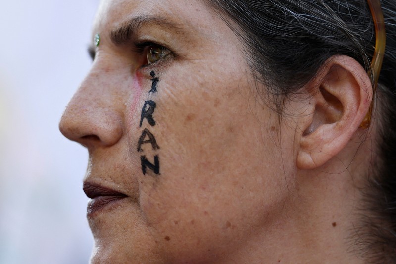 Marinir AS berjaga saat seorang demonstran memegang plakat selama protes terhadap Amerika Serikat yang bergabung dengan Israel dalam serangan terhadap fasilitas nuklir Iran, di gedung federal di Los Angeles, California, AS, 22 Juni 2025. (REUTERS/David Swanson)