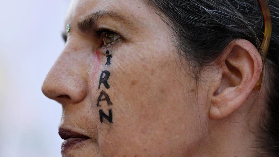 Marinir AS berjaga saat seorang demonstran memegang plakat selama protes terhadap Amerika Serikat yang bergabung dengan Israel dalam serangan terhadap fasilitas nuklir Iran, di gedung federal di Los Angeles, California, AS, 22 Juni 2025. (REUTERS/David Swanson)