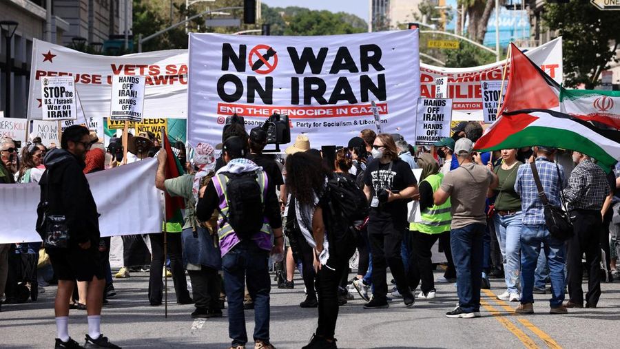 Marinir AS berjaga saat seorang demonstran memegang plakat selama protes terhadap Amerika Serikat yang bergabung dengan Israel dalam serangan terhadap fasilitas nuklir Iran, di gedung federal di Los Angeles, California, AS, 22 Juni 2025. (REUTERS/David Swanson)