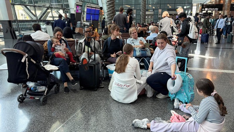 Orang-orang duduk di Bandara Internasional Hamad setelah Qatar membuka kembali wilayah udaranya setelah penutupan singkat akibat serangan rudal Iran di Pangkalan Udara Al Udeid pada hari Senin, di Doha, Qatar, 24 Juni 2025. (REUTERS/Stringer)