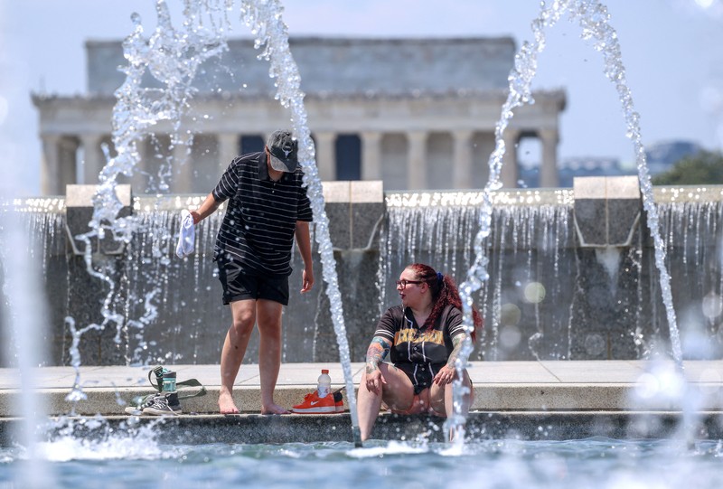 Seorang pengunjung National Mall memegang payung untuk melindungi diri dari terik matahari, di tengah gelombang panas berbahaya yang melanda wilayah timur Amerika Serikat, di Washington, D.C., AS, 25 Juni 2025. (REUTERS/Kevin Lamarque)