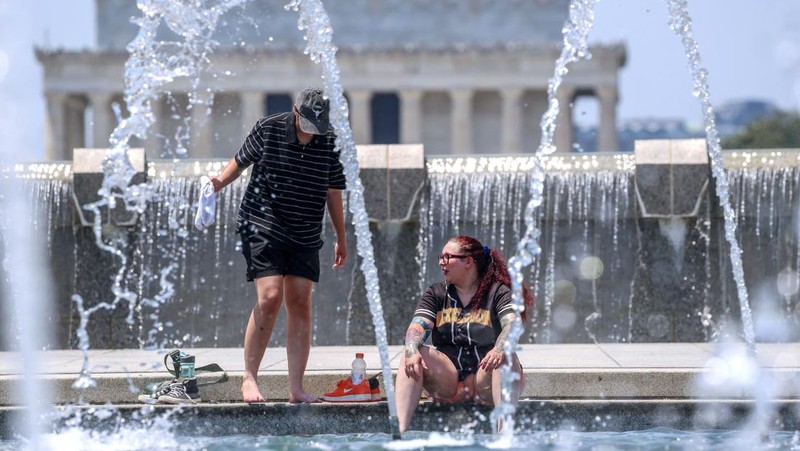 Seorang pengunjung National Mall memegang payung untuk melindungi diri dari terik matahari, di tengah gelombang panas berbahaya yang melanda wilayah timur Amerika Serikat, di Washington, D.C., AS, 25 Juni 2025. (REUTERS/Kevin Lamarque)
