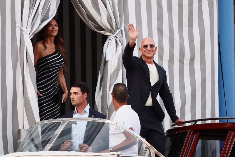 Jeff Bezos dan Lauren Sanchez menaiki perahu saat meninggalkan hotel Aman Venice, menjelang pernikahan mereka yang direncanakan, di Venesia, Italia, 25 Juni 2025. (REUTERS/Guglielmo Mangiapane)