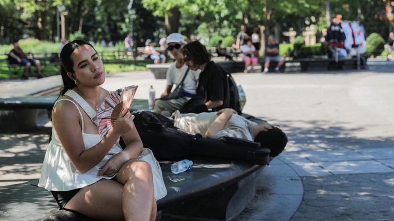 Seorang pengunjung National Mall memegang payung untuk melindungi diri dari terik matahari, di tengah gelombang panas berbahaya yang melanda wilayah timur Amerika Serikat, di Washington, D.C., AS, 25 Juni 2025. (REUTERS/Kevin Lamarque)