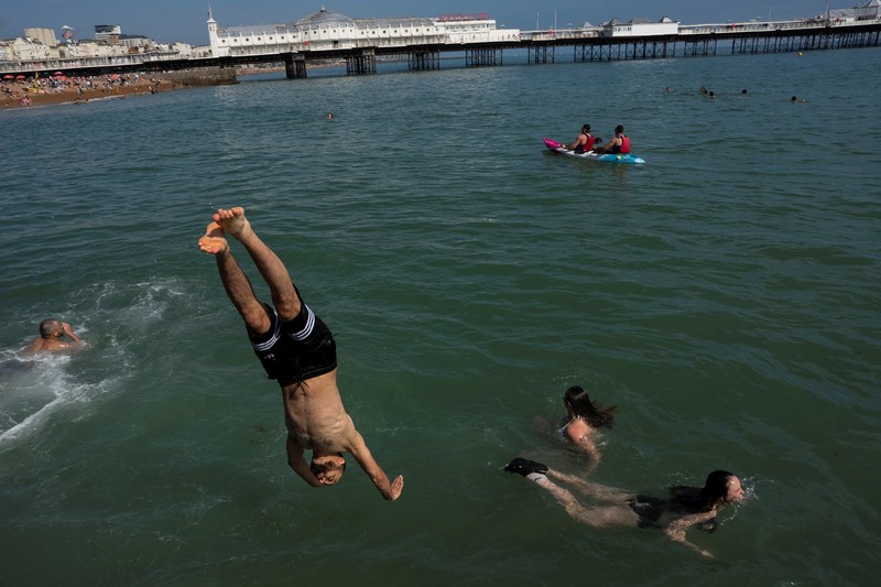 Seorang pria menyelam ke laut dekat Dermaga Istana Brighton saat cuaca panas di Brighton, Inggris, Minggu (29/6/2025). (REUTERS/Carlos Jasso)