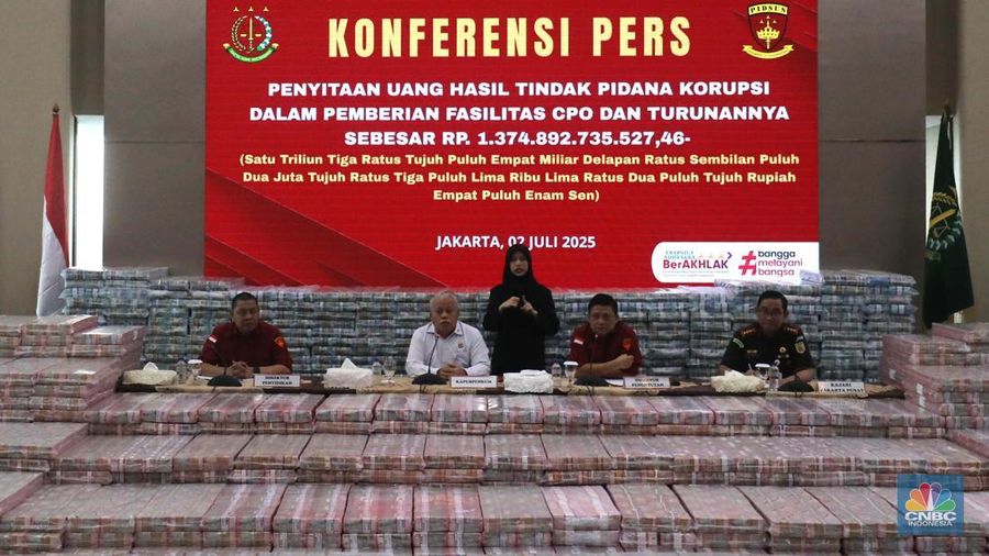 Petugas berjaga di samping tumpukan uang yang menjadi barang bukti uang sitaan saat konferensi pers kasus korupsi ekspor crude palm oil (CPO) di Gedung Bundar Jampidus Kejaksaaan Agung (Kejagung), Jakarta, Rabu (2/7/2025). (CNBC Indonesia/Muhammad Sabki)