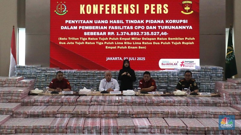 Petugas berjaga di samping tumpukan uang yang menjadi barang bukti uang sitaan saat konferensi pers kasus korupsi ekspor crude palm oil (CPO) di Gedung Bundar Jampidus Kejaksaaan Agung (Kejagung), Jakarta, Rabu (2/7/2025). (CNBC Indonesia/Muhammad Sabki)