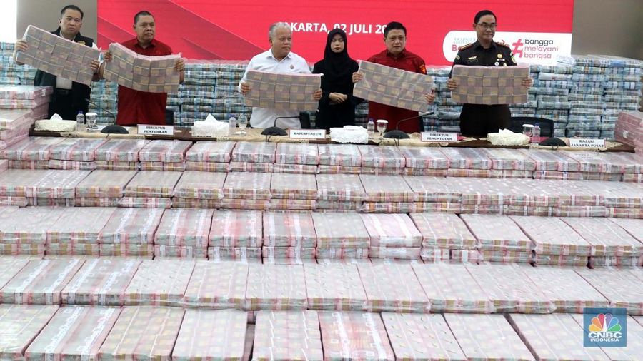 Petugas berjaga di samping tumpukan uang yang menjadi barang bukti uang sitaan saat konferensi pers kasus korupsi ekspor crude palm oil (CPO) di Gedung Bundar Jampidus Kejaksaaan Agung (Kejagung), Jakarta, Rabu (2/7/2025). (CNBC Indonesia/Muhammad Sabki)