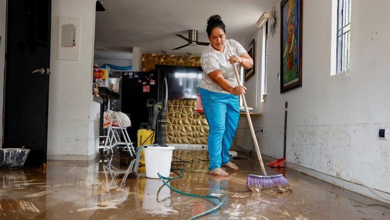 Seorang pria menjaga barang-barang miliknya di jalan setelah hujan lebat di Villavicencio, Kolombia, 1 Juli 2025. (REUTERS/Santiago Molina Fernandez)