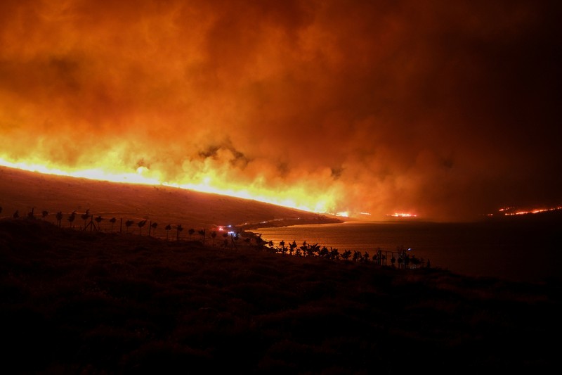 Seorang wanita bereaksi saat mencoba meninggalkan daerah tersebut dengan skuternya, selama kebakaran hutan di dekat Alacati, di provinsi Izmir, Turki, 3 Juli 2025. (REUTERS/Murat Kocabas)