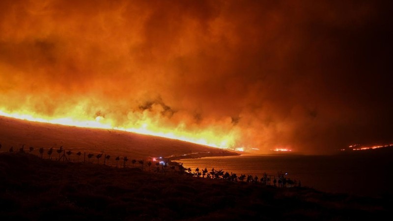Seorang wanita bereaksi saat mencoba meninggalkan daerah tersebut dengan skuternya, selama kebakaran hutan di dekat Alacati, di provinsi Izmir, Turki, 3 Juli 2025. (REUTERS/Murat Kocabas)