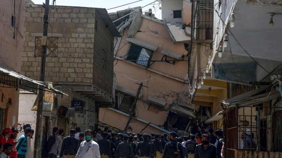 Petugas keamanan Pakistan berkumpul di samping bangunan tempat tinggal lima lantai yang runtuh di Karachi. (AFP/ASIF HASSAN)