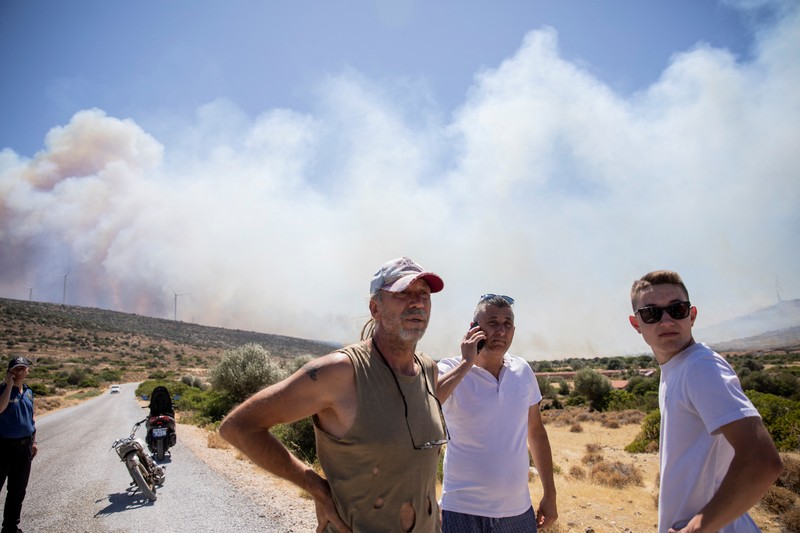 Seorang wanita bereaksi saat mencoba meninggalkan daerah tersebut dengan skuternya, selama kebakaran hutan di dekat Alacati, di provinsi Izmir, Turki, 3 Juli 2025. (REUTERS/Murat Kocabas)