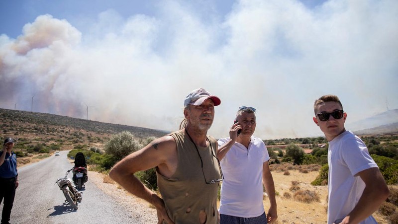 Seorang wanita bereaksi saat mencoba meninggalkan daerah tersebut dengan skuternya, selama kebakaran hutan di dekat Alacati, di provinsi Izmir, Turki, 3 Juli 2025. (REUTERS/Murat Kocabas)