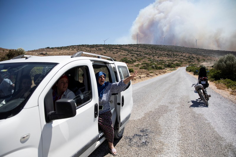 Seorang wanita bereaksi saat mencoba meninggalkan daerah tersebut dengan skuternya, selama kebakaran hutan di dekat Alacati, di provinsi Izmir, Turki, 3 Juli 2025. (REUTERS/Murat Kocabas)