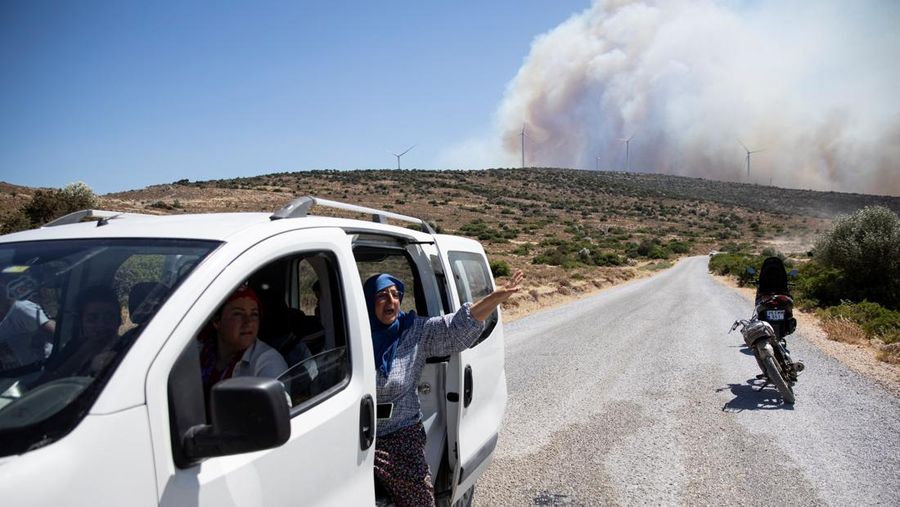 Seorang wanita bereaksi saat mencoba meninggalkan daerah tersebut dengan skuternya, selama kebakaran hutan di dekat Alacati, di provinsi Izmir, Turki, 3 Juli 2025. (REUTERS/Murat Kocabas)