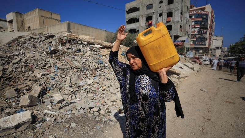 Seorang pria Palestina, yang mengungsi akibat serangan Israel, memandikan putranya di dalam tempat penampungan mereka di tengah teriknya musim panas, di Kota Gaza, 3 Juli 2025. (REUTERS/Dawoud Abu Alkas)