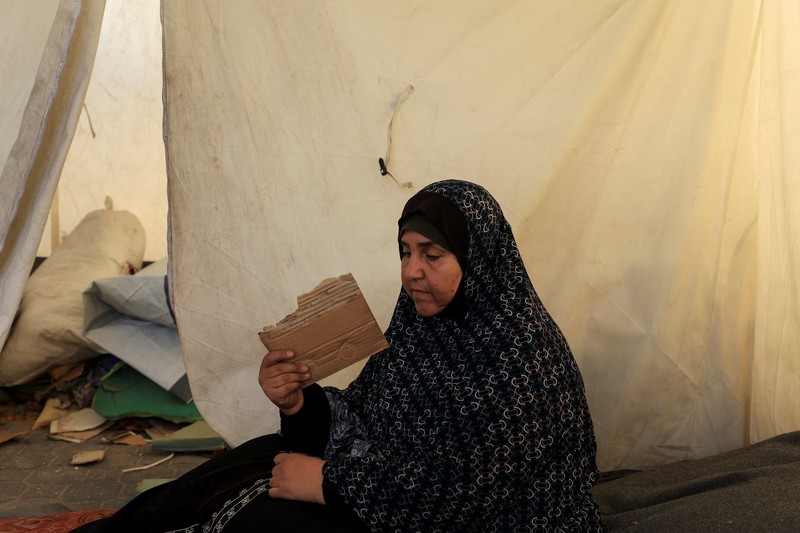 Seorang pria Palestina, yang mengungsi akibat serangan Israel, memandikan putranya di dalam tempat penampungan mereka di tengah teriknya musim panas, di Kota Gaza, 3 Juli 2025. (REUTERS/Dawoud Abu Alkas)