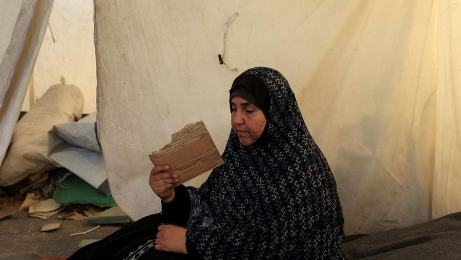 Seorang pria Palestina, yang mengungsi akibat serangan Israel, memandikan putranya di dalam tempat penampungan mereka di tengah teriknya musim panas, di Kota Gaza, 3 Juli 2025. (REUTERS/Dawoud Abu Alkas)