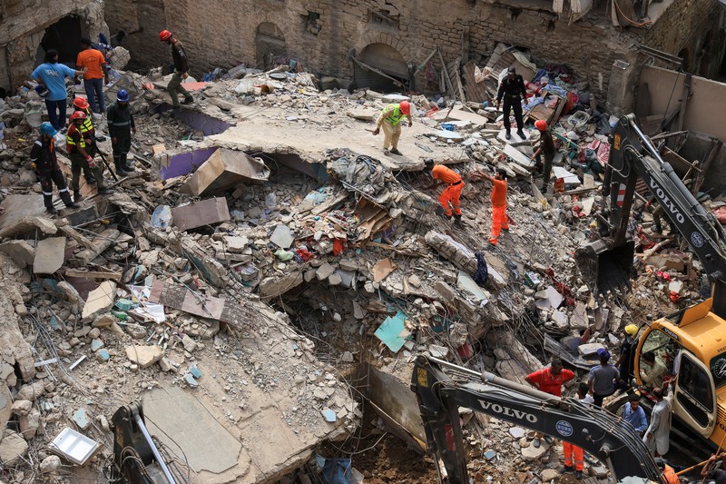 Petugas penyelamat mencari korban selamat saat mereka melewati reruntuhan bangunan tempat tinggal lima lantai yang runtuh di Karachi, Pakistan, 4 Juli 2025. (REUTERS/Akhtar Soomro)