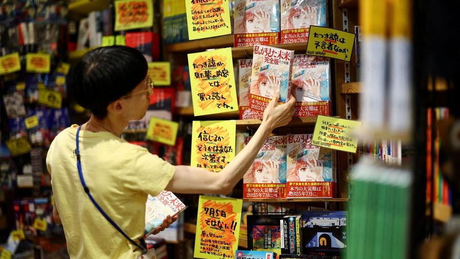 Seorang anggota staf meletakkan buku komik berjudul 'The Future I saw', yang ditulis oleh seniman manga Ryo Tatsuki, di rak toko buku Village Vanguard di Tokyo, Jepang, 30 Juni 2025. (REUTERS/Issei Kato)
