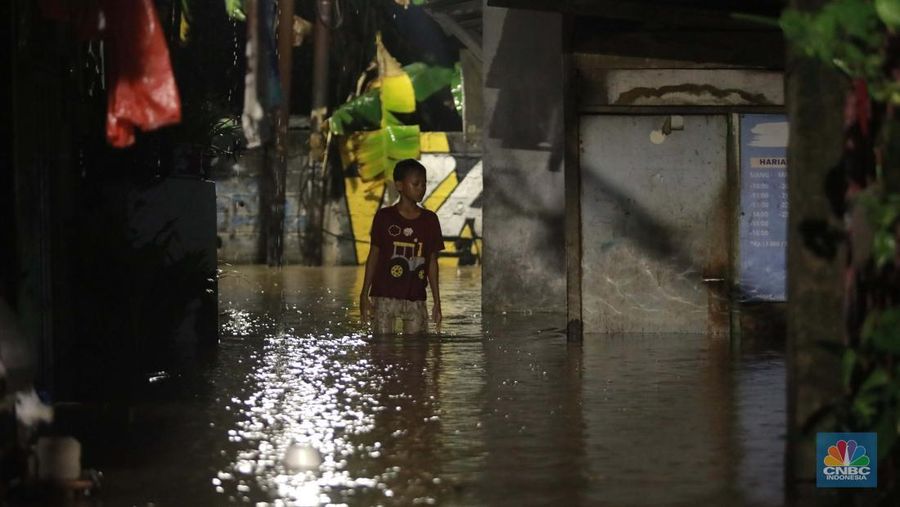 Sejumlah warga melintas di tengah banjir di RW 06 Jatipadang, Jakarta Selatan, (6/7/2025). (CNBC Indonesia/Muhammad Sabki)