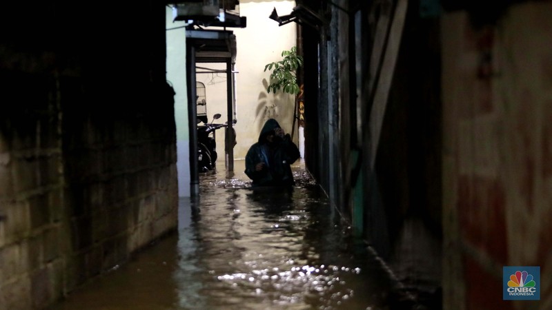 Sejumlah warga melintas di tengah banjir di RW 06 Jatipadang, Jakarta Selatan, (6/7/2025). (CNBC Indonesia/Muhammad Sabki)