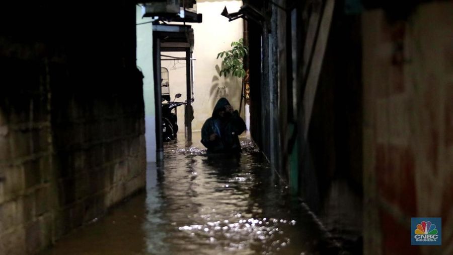Sejumlah warga melintas di tengah banjir di RW 06 Jatipadang, Jakarta Selatan, (6/7/2025). (CNBC Indonesia/Muhammad Sabki)