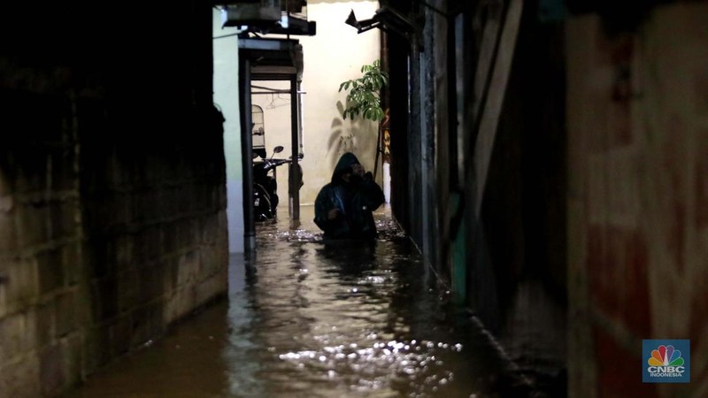 Sejumlah warga melintas di tengah banjir di RW 06 Jatipadang, Jakarta Selatan, (6/7/2025). (CNBC Indonesia/Muhammad Sabki)