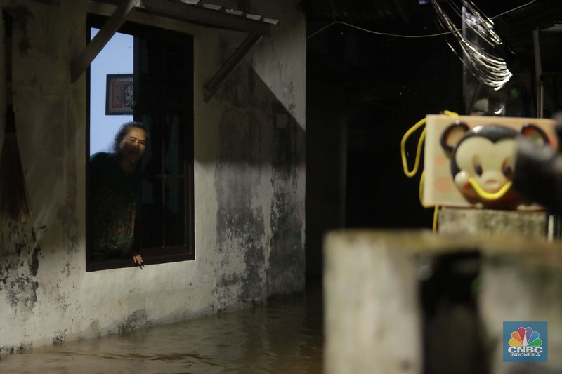 Sejumlah warga melintas di tengah banjir di RW 06 Jatipadang, Jakarta Selatan, (6/7/2025). (CNBC Indonesia/Muhammad Sabki)