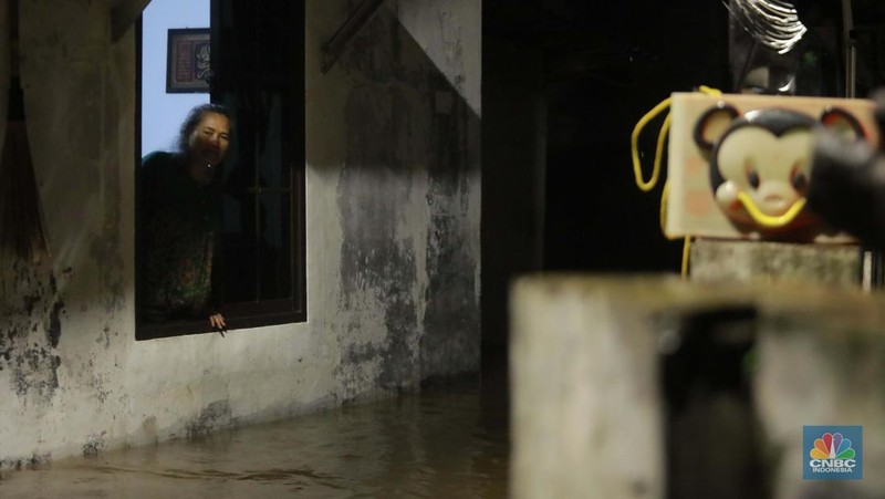 Sejumlah warga melintas di tengah banjir di RW 06 Jatipadang, Jakarta Selatan, (6/7/2025). (CNBC Indonesia/Muhammad Sabki)