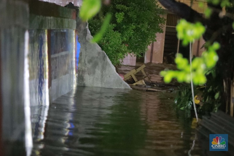 Sejumlah warga melintas di tengah banjir di RW 06 Jatipadang, Jakarta Selatan, (6/7/2025). (CNBC Indonesia/Muhammad Sabki)