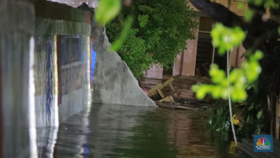 Sejumlah warga melintas di tengah banjir di RW 06 Jatipadang, Jakarta Selatan, (6/7/2025). (CNBC Indonesia/Muhammad Sabki)