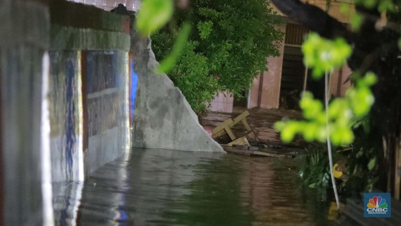 Sejumlah warga melintas di tengah banjir di RW 06 Jatipadang, Jakarta Selatan, (6/7/2025). (CNBC Indonesia/Muhammad Sabki)