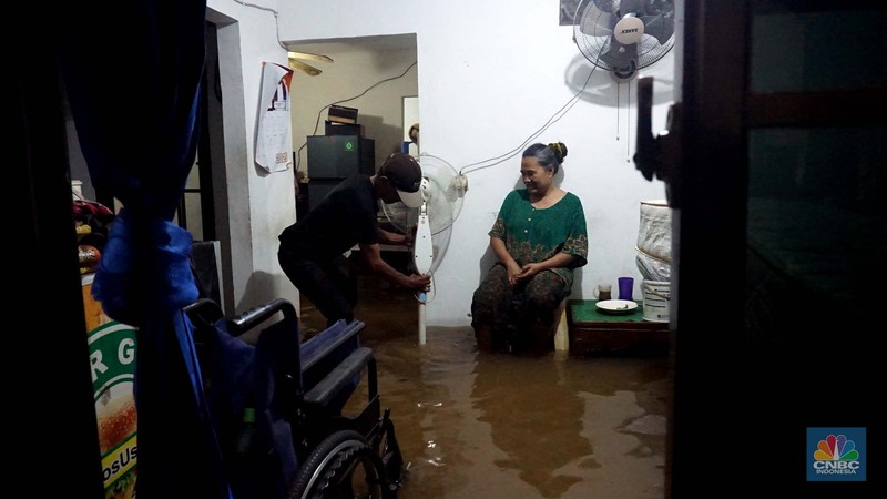 Sejumlah warga melintas di tengah banjir di RW 06 Jatipadang, Jakarta Selatan, (6/7/2025). (CNBC Indonesia/Muhammad Sabki)
