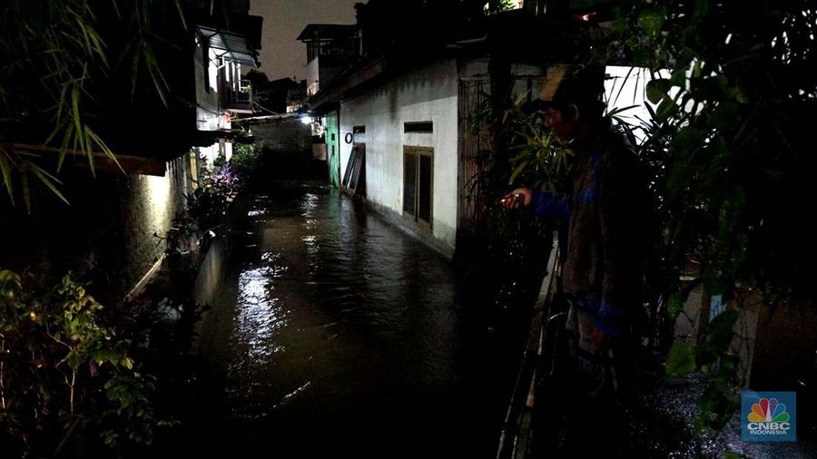 Sejumlah warga melintas di tengah banjir di RW 06 Jatipadang, Jakarta Selatan, (6/7/2025). (CNBC Indonesia/Muhammad Sabki)